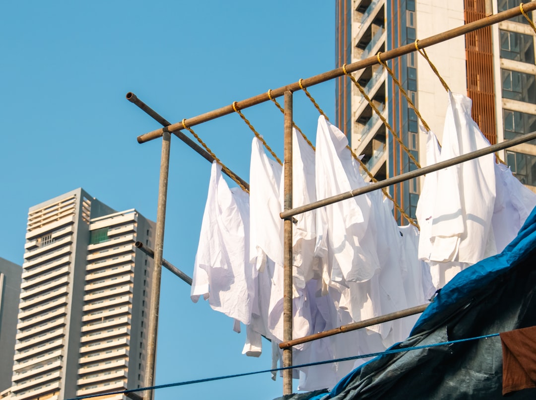 White bedsheets hang on a clothes line at Mumbai's Dhobi Ghat, Mumbai's iconic open-air laundromat, located near Mahalaxmi station, that is one of the world's largest of its kind. The washers, known as dhobis, work in the open to wash clothes and linens from Mumbai's hotels and hospitals. Over one lakh (100,000) clothes are washed each day. Some of the wealthier dhobis have given up on manual cleaning and have now installed large mechanical washing and drying machines. The dhobis collect clothes from all parts of the city, from Colaba to Virar.