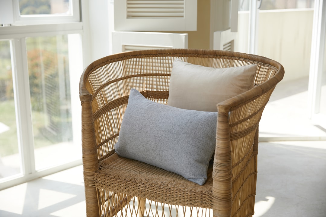 Comfortable cane chair with cushions by the window